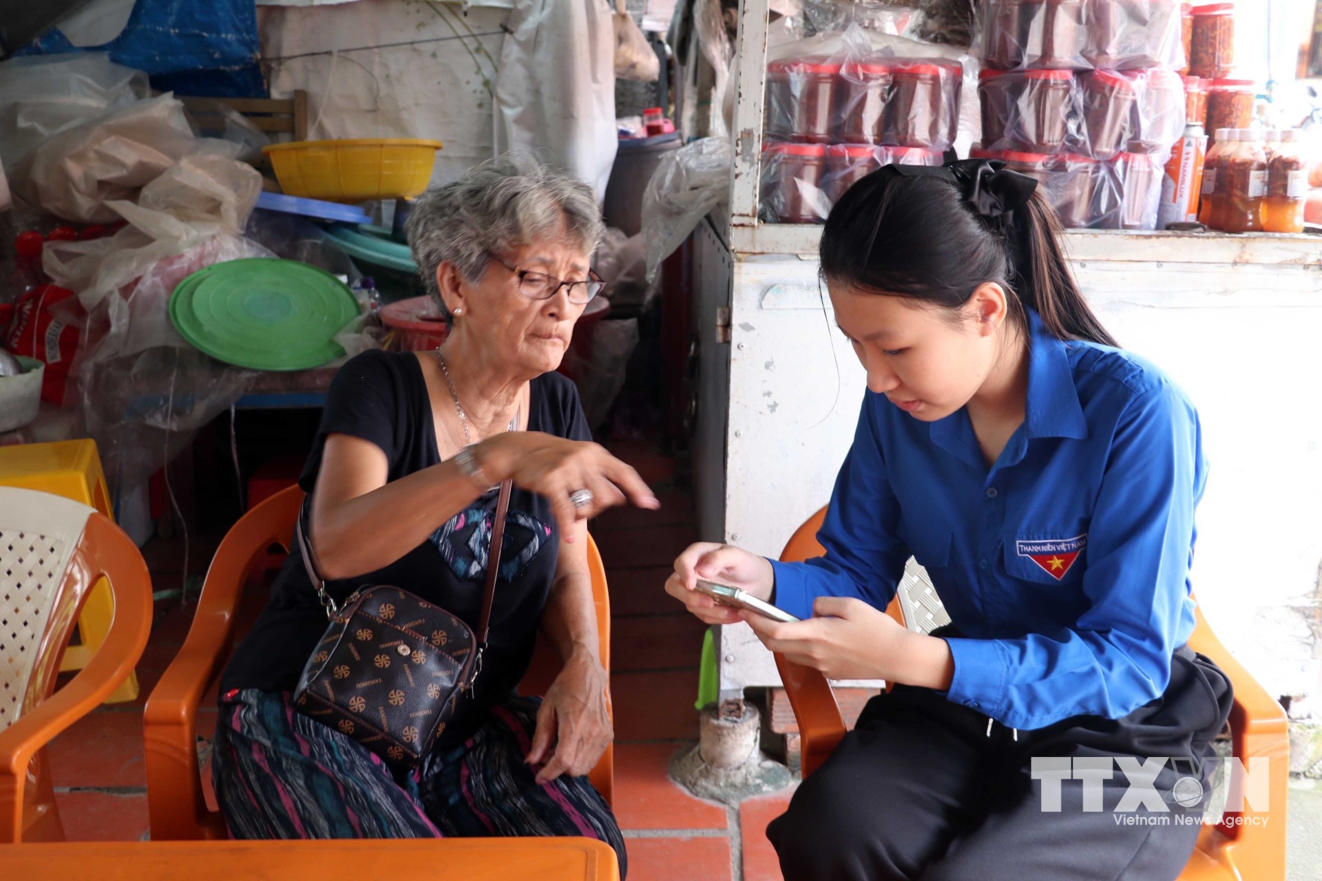 Tổ công nghệ số Đoàn Thanh niên xã Long Sơn cài đặt và hướng dẫn tiểu thương tại khu vực bán hàng hải sản phía trước Nhà lớn Long Sơn. (Ảnh: Đoàn Mạnh Dương/TTXVN)